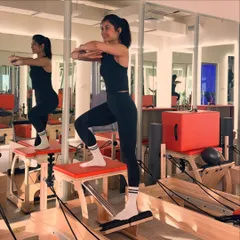 The Pilates chair is a versatile piece of equipment. Here, I use it for a standing step-up exercise that challenges balance, leg strength, and core control.