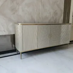 This metallic finish buffet console is a testament to modern elegance. We designed it with clean, fluted textures and fine conical steel legs to create a statement piece that offers both significant storage and a sophisticated aesthetic for dining or living areas.
