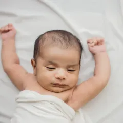 The color version of the sleepy stretch, showing the baby's beautiful skin tone against the soft white fabric.