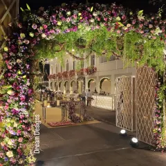 A lush and inviting entrance for an evening event. The dense floral arch is lit from within, creating a warm glow that leads guests into the main celebration area.