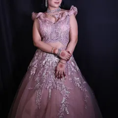 A beautiful engagement gown in a dusty pink hue. The bodice is heavily embellished with intricate beadwork, and the ruffled shoulders add a touch of modern romance.