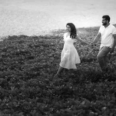 A candid black and white photo of a couple walking along the water's edge. The monochrome style gives this simple, happy moment a classic, storybook quality.