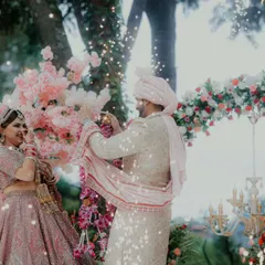 A magical moment from a destination wedding in Bhimtal, with the couple exchanging garlands under a shower of sparkles and a beautiful floral arch.