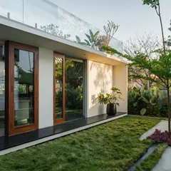 The Long House features a seamless transition from the interior to the lawn, with large glass doors and a continuous ground plane.