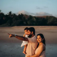 A family of three stands on the beach at sunset, the father pointing towards the horizon. This image tells a story of discovery and shared experience, a key part of our documentary family photography approach.