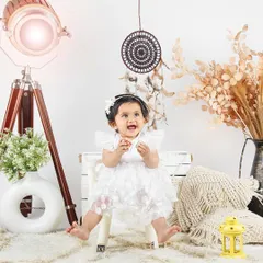 This baby girl in her beautiful white dress looks like a little angel. The simple, boho-inspired setup keeps the focus entirely on her.