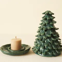 The Coniferous Christmas tree luminary next to a small candle. Once lit, the light flickers through the individually attached clay leaves, creating a magical effect.