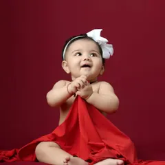 A simple and classic portrait of a sitting baby against a rich red backdrop. Her curious expression and sweet pose make this a timeless image.