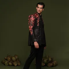 Make a bold statement with a designer Indo-Western piece. This professionally shot look features a black sequined jacket with vibrant floral embroidery on the shoulders, perfect for a sangeet or reception.