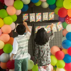 Teamwork makes the dream work. Kids helping to set up the 'Happy Birthday' banner is a sweet, candid moment from the party preparations.
