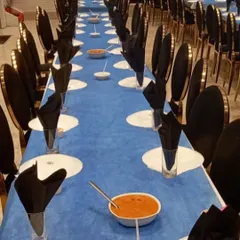 A long view of our formal dining setup. The striking blue and black theme, with neatly folded napkins and pre-set dishes, shows our ability to execute a sophisticated and large-scale seated dinner service.