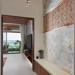 In the Sobha Indraprastha apartment, the foyer features a wall clad in onyx marble with a CNC-cut wooden panel. This decorative panel is strategically designed to hide the electrical board while adding to the aesthetic.