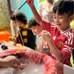 Success! This boy is thrilled as he 'fishes' for a spooky toy in a bubbling cauldron during our Halloween science activity.