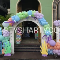 An elaborate entrance designed to look like an underwater castle, with balloon arches, seaweed props, and a personalized welcome sign.