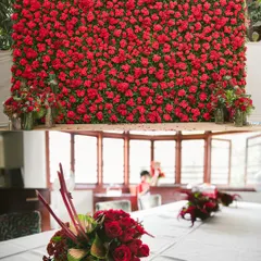 Impactful branding is key. The top image features a floor-to-ceiling wall of red roses, creating an unforgettable photo opportunity for a product launch or gala. The bottom image shows how this theme extends to elegant table centerpieces for a cohesive brand environment.