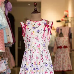 A lovely floral dress with unique shoulder-tie details. This piece, shown on a mannequin, highlights a playful and modern design perfect for a sunny day.