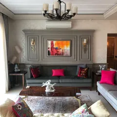 We used pops of vibrant color against a neutral gray backdrop to create a lively yet elegant living room. The custom wall paneling adds a classical touch and serves as a sophisticated frame for the artwork and wall sconces.