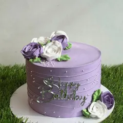 Another view of our elegant purple floral cake, showcasing the beautiful arrangement of hand-piped whipped cream roses.