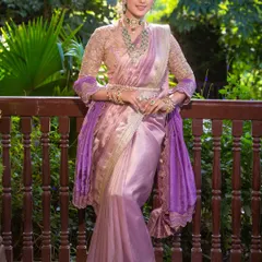 A full-length portrait showcasing the beautiful drape of the lilac saree against a lush green backdrop. The makeup is designed to look flawless and glowing even in natural daylight.