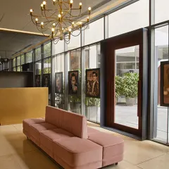The theater lobby at Rustomjee Elements features a pink sofa and portraits of film icons. The glass facade allows these details to be viewed from both inside and out, creating a welcoming and thematic entrance.