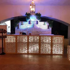A stylish, custom-built bar is essential for networking and celebration. This illuminated bar counter features intricate latticework and is complemented by a personalized logo backdrop, creating a central hub for your guests to connect.