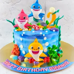 Baby Shark doo doo doo. This vibrant underwater cake features the whole Baby Shark family, handcrafted from fondant. The design uses an airbrushing technique on buttercream to create the blue ocean effect.