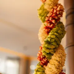 A close-up of a traditional South Indian garland, meticulously handwoven from coconut leaves, jasmine, and firecracker flowers. This type of detailed floral craftsmanship is a signature element I use to bring authenticity and beauty to wedding decor.