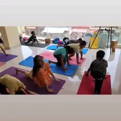 Young students practice a modified version of Pigeon Pose, an excellent asana for improving hip flexibility and posture. We guide each child to ensure proper form and safety while they explore their physical capabilities.