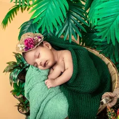 Your newborn's first photoshoot should be as unique as they are. I designed this tropical-themed setup with lush greens and a cozy basket to create a peaceful, artistic portrait of this sleeping baby.