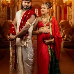 A powerful and regal portrait of a couple dressed in historic royal attire, complete with a sword and ornate jewelry, set against a palace backdrop.