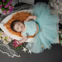 A little fashionista in the making. This baby girl is dressed in a beautiful blue tutu, looking calm and content during her styled studio session.