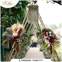 A rustic and chic entrance walkway created with a triangular bamboo structure. The path is decorated with pampas grass, floral bouquets, and macrame chandeliers.