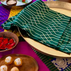 The green brocade placemat, a perfect complement to the colorful Bandhani runner and silk tablecloth.