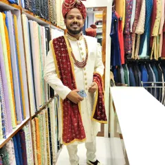 A smiling groom trying on his final wedding attire in my studio. This classic off-white sherwani is perfectly complemented by a rich maroon velvet stole, creating a sophisticated contrast.