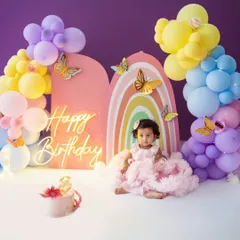 A beautiful rainbow and butterfly theme for this little girl's first birthday. The pastel balloon arch and neon sign create a magical backdrop for her special day.