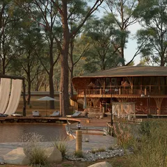 The main lodge and pool area are seen here, surrounded by the lush greenery of the property. The design emphasizes open-air living, with wide balconies and decks that invite guests to enjoy the natural setting from every vantage point.
