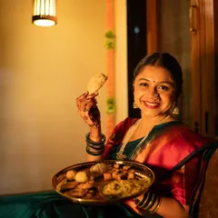 What is Diwali without the delicious homemade snacks? Here, she joyfully holds up a 'karanji' from a plate full of 'faral', a shot that is both a beautiful portrait and a celebration of festive traditions.