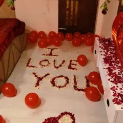 The floor of this romantic setup features 'I LOVE YOU' written with white and red rose petals, along with a petal heart. It's a classic and heartfelt gesture.