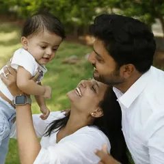 The pure joy of being together. An outdoor family session filled with laughter as a mother lifts her baby high, sharing a beautiful moment with her partner.