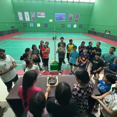 A high-angle shot of our students gathered around the cake for World Badminton Day. These moments of unity and joy are what build our strong community.