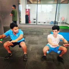 Strength and conditioning are integral to our training. I am seen here doing squats alongside a young athlete, emphasizing the importance of leading by example in physical fitness.