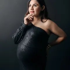 A thoughtful and chic portrait of an expecting mother in a black sequin dress. Her pose and expression convey a sense of wonder and anticipation for the future.