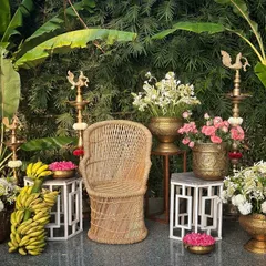 Our classic South Indian photo booth setup, featuring a traditional wicker chair, brass vessels, and banana plants for an authentic touch.