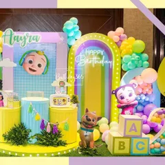 A closer look at the Cocomelon party stage, featuring JJ, his dog Bingo, and other characters, along with a rainbow arch and large ABC blocks.
