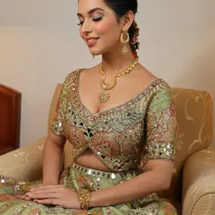 The complete picture of a happy Mehendi bride. The soft, glowing makeup and elegant updo perfectly complement her ornate green lehenga, creating a look of pure joy.