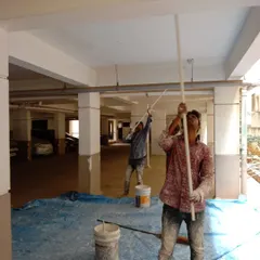 Our team at work on a large commercial project, painting the ceiling of an apartment building's parking garage. We use rollers with long extensions to ensure even coverage on high ceilings and large surfaces.