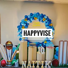 A cricket-themed 10th birthday for Naitik. The setup includes cutouts of wickets and a trophy, with a blue and gold balloon circle creating a winner's circle for the birthday boy.