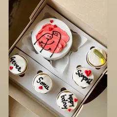 This adorable combo celebrates love with a bento cake showing two stick figures hugging, surrounded by five cupcakes. The cupcakes are personalized with names like 'Sonu' and 'Swapnil' and messages like '4ever' and 'happy bday'.
