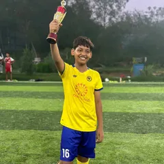 A player confidently holds his trophy high, celebrating a significant achievement in his football journey.