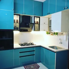 A bold and vibrant modular kitchen design. The high-gloss turquoise and white acrylic cabinets create a fresh and energetic atmosphere, complemented by a marble-patterned backsplash and smart storage solutions.